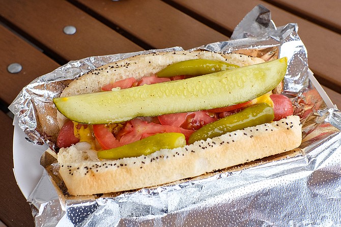 Chicago style hot dog on a poppy seed bun with mustard, onions, tomatoes, sports pepper, pickle, and celery salt
