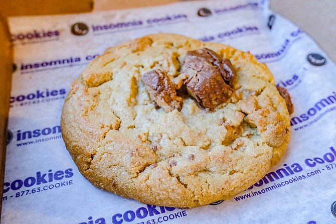 A chocolate peanut butter cup cookie, served warm in a mini pizza box