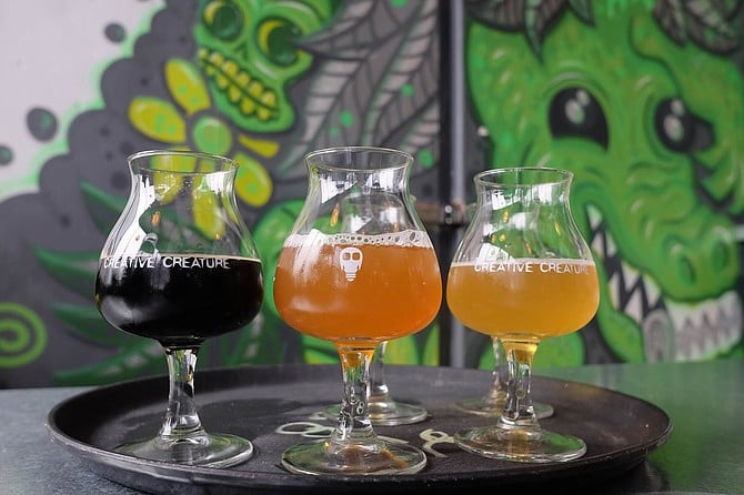 A flight of beers overseen by grinning monsters and skulls at Creative Creature brewing