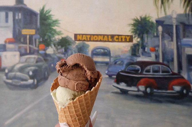 A cone filled with avocado and red ale Mexican chocolate ice cream, in front of a National City mural inside Niederfrank's Ice Cream