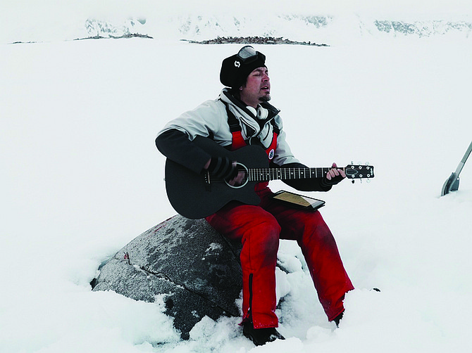 Pablo Cantua sings in Antarctica. Audience of penguins behind him.