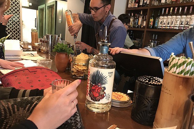Tequilas and mezcals pouring out during frantic Friday happy hour