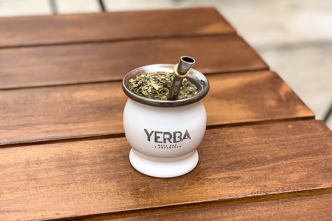 Dry yerba leaves float to the top of a mate freshly filled with hot water, and ready to sip through the bombilla.