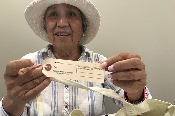 Eileen Oya holds I/D tag like the one she and her family had to wear when they were transported to internment camp in Arizona in 1942