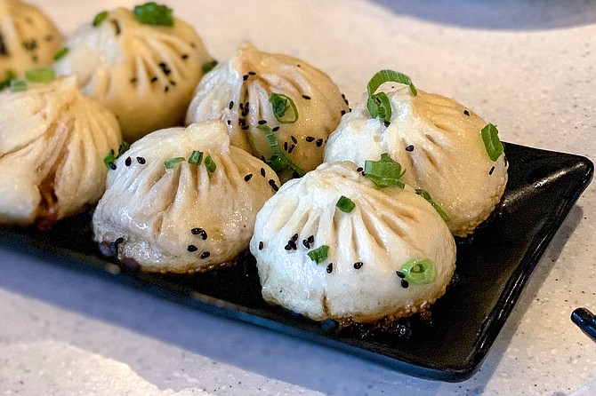 Grilled pork buns dressed with green onions, black sesame seeds, and caramelized white sesame seeds