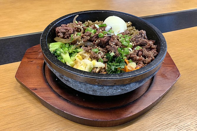 Hot stone bowl of seaweed rice, mixed vegetables, bulgogi beef, and a sous vide egg