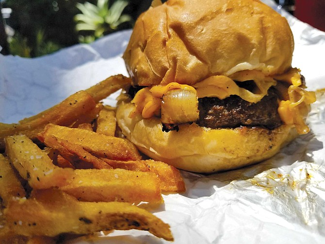 At Sister Ray’s melted American cheese mingles with a sloppy heap of lightly caramelized onions, all squished between fluffy buns that soak up juices from a charred yet tender beef patty.