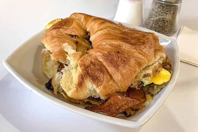 The All American brings together bacon, eggs, potatoes, and a croissant.