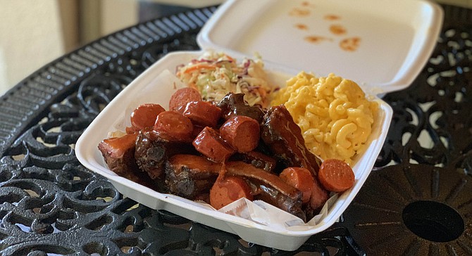 A sampler of ribs, brisket, and sliced hot links with coleslaw and macaroni