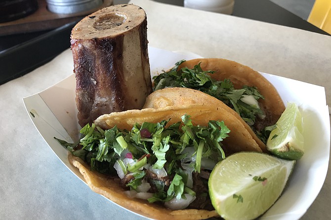 The upstanding beef bone is impressive, but the birria tacos hold the golden prize here