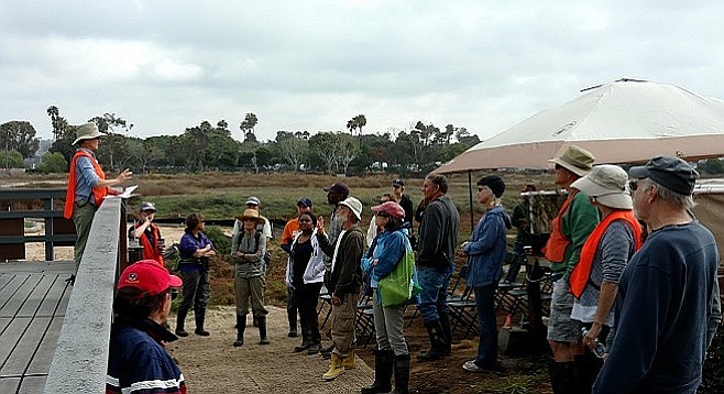 Visitors and volunteers gather before embarking on a morning marsh tour.
