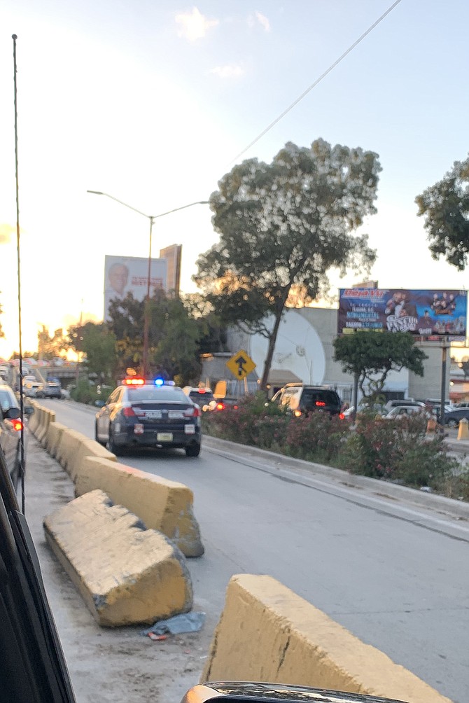 A Tijuana police cruiser passes a concrete barrier that has been moved to allow access to the border line.