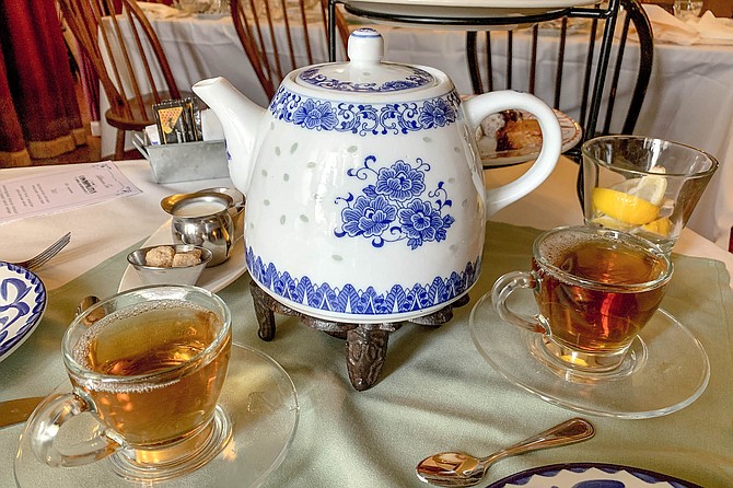 Cups of assam tea poured from a traditional blue and white floral teapot