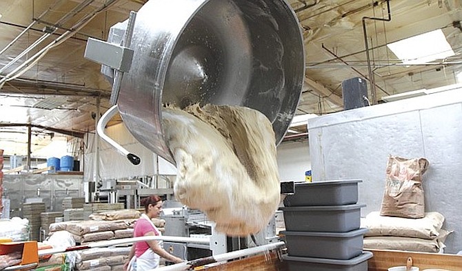 A mixing bowl lift drops 300 lbs. of dough onto a table. It will be cut and placed in plastic bins to be sent to a temperature-controlled proofing room for the dough to rise.