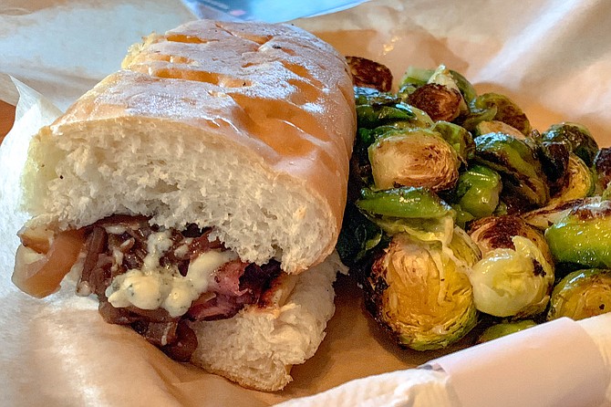 Roast beef and blue cheese sandwich with brussels sprouts on the side
