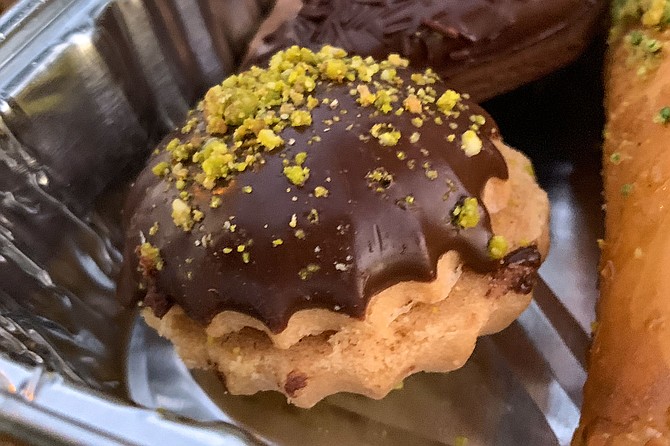A chocolate-dipped sandwich cookie encrusted with pistachio