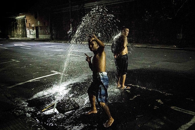 In the hours before dawn, grown men play in the spray of cracked water lines.