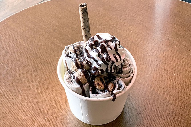 Rolled cookies and cream ice cream with chocolate syrup, whipped cream, and cookie cereal toppings
