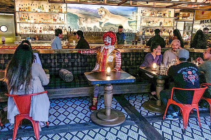 A satirical Ronald McDonald statue buffers socially distanced parties at Craft & Commerce.