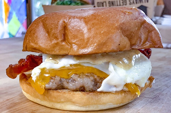 A breakfast sandwich bigger than a double double, with bacon, sausage, fried egg, and cheddar on brioche bun.