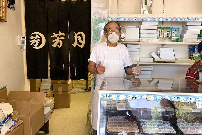 A masked Masa Takeda, standing in his Japanese tea cake shop of 37 years