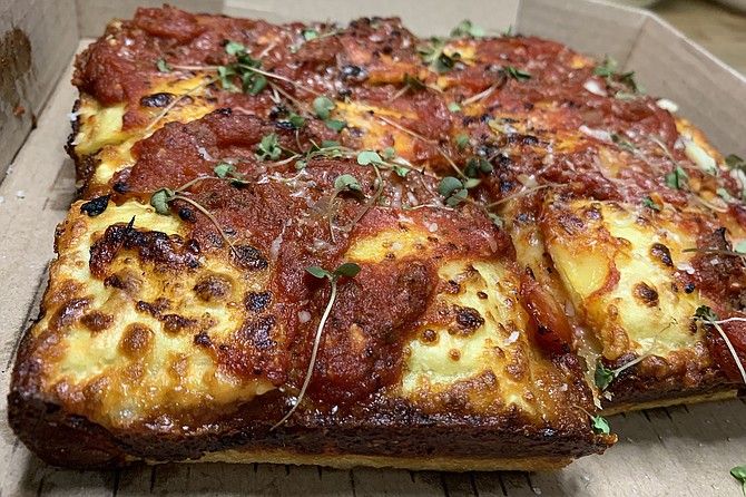 The rectangular, Detroit style pizza, topped by cheese ravioli and meat sauce