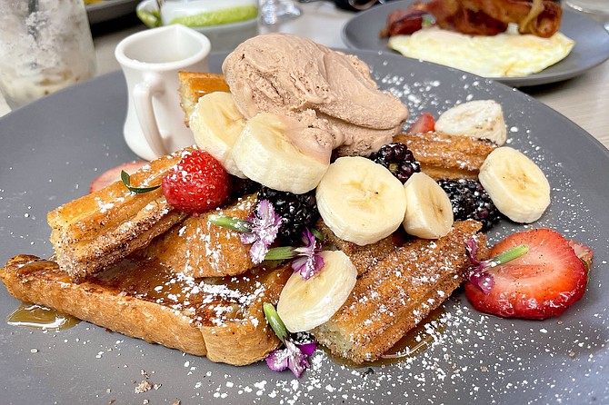 Churros and French toast, topped with fruit, caramel sauce, and dulce de leche ice cream