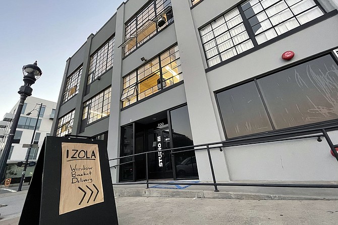 Sidewalk signs for Izola Bakery are a clue to look up for the basket hanging out a third story window.