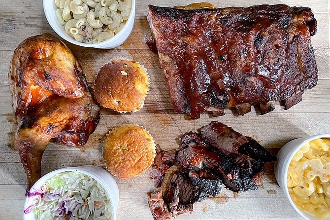 A BBQ take out order, including smoked chicken, brisket, pork ribs, mac and cheese, coleslaw, macaroni salad, and jalapeño corn muffins.