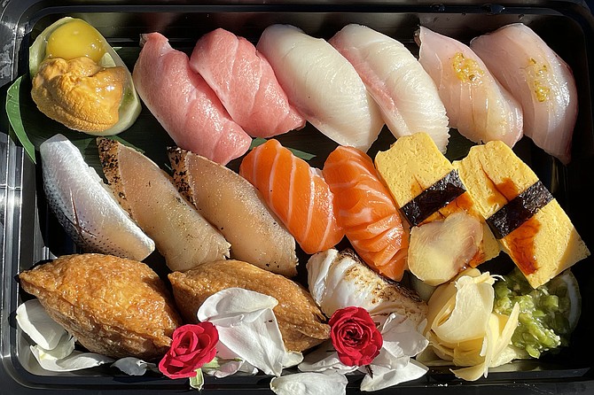 A box of "bomb cuts" sushi. Top row (left to right): Uni and quail egg, bluefin tuna belly, yellowtail belly, white sea bass. Middle row: gizzard shad, seared albacore, Atlantic salmon, tamago. Bottom row: crab inari, seared sea bream, pickled wasabi).