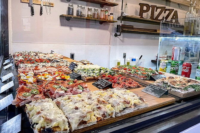 Roman pizza, also known as pinsa, slices arranged in the window of Gelati & Peccati