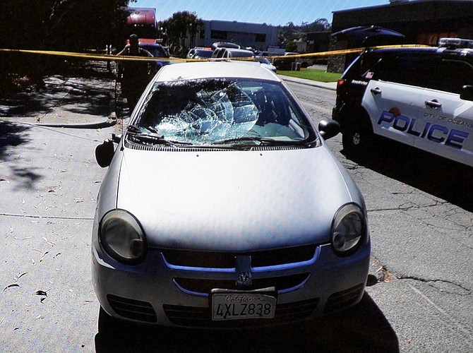 Evidence photo of the car w smashed windshield, it contains the officer's radio.