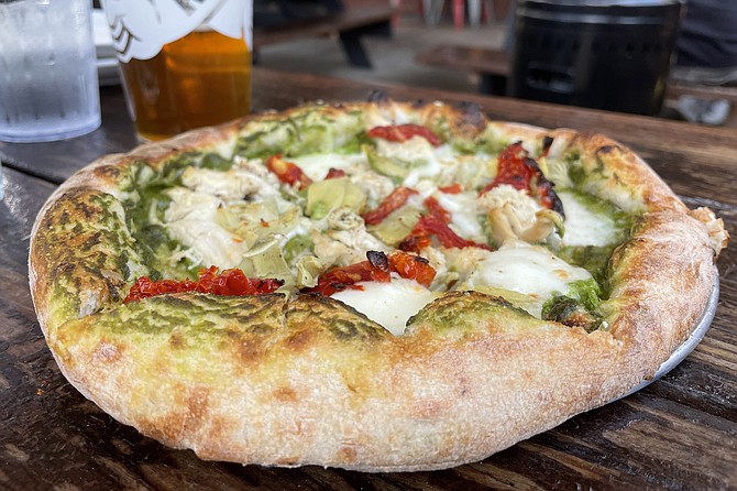 The Privateer signature pizza, featuring chicken, sun-dried tomatoes, and artichoke with a walnut pesto sauce