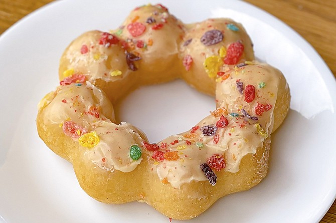 A mango glazed mochinut topped with Fruity Pebbles cereal