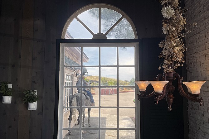 A cowboy guides his horse outside the restaurant window.