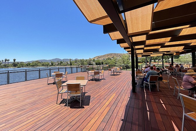 Afternoon visitors fill the shaded side of the lakeside deck.
