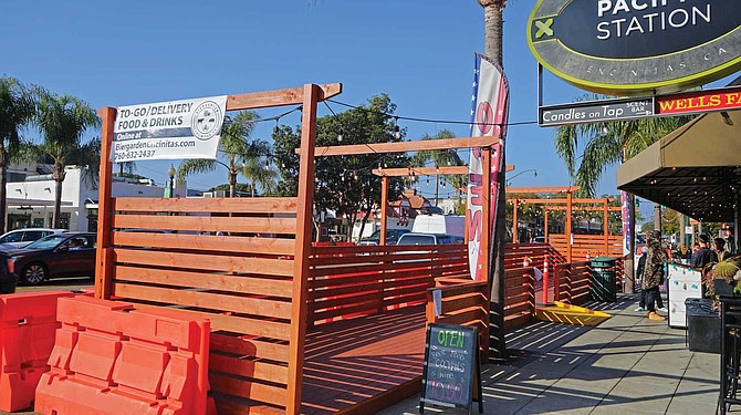 Curbside dining in Encinitas. Sidewalk customers protected by orange barriers.