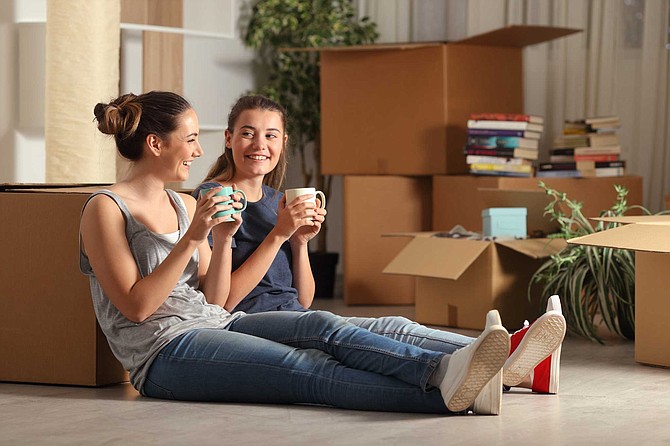 Roommates drinking coffee next to moving boxes