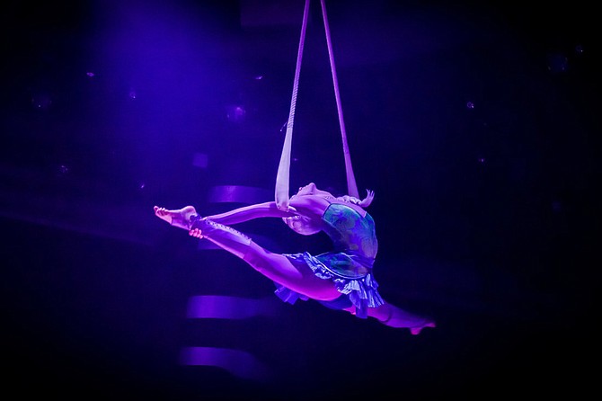 a woman hanging from rope doing the splits mid-air