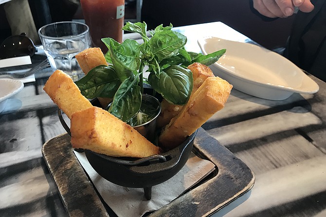 Fried polenta sticks with bowl of pesto.