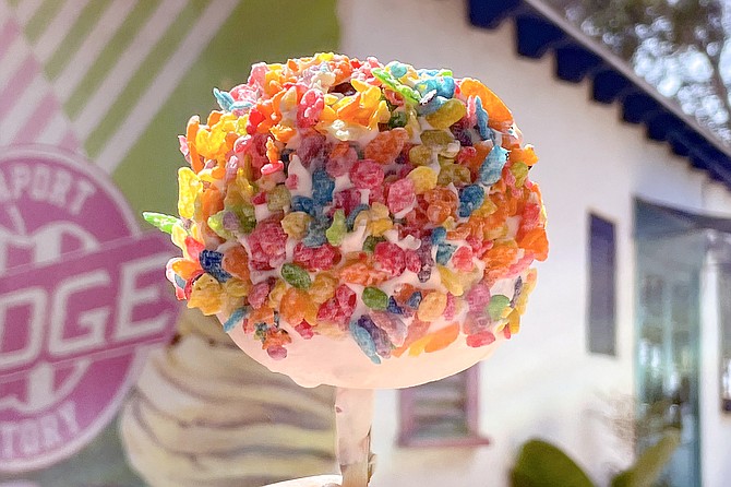 A candied apple dipped in caramel, white chocolate, and Fruity Pebbles breakfast cereal