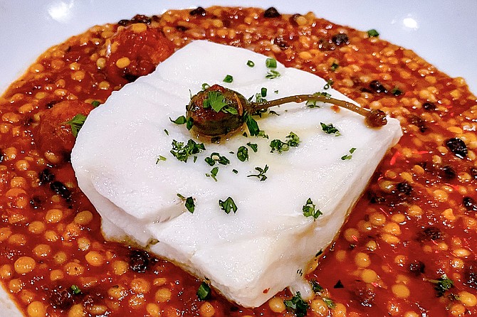 Chilean sea bass and pearled couscous in tomato broth, topped by a caper berry