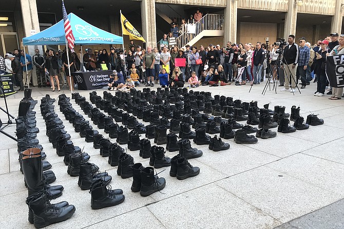 Firefighters’ and cops’ boots symbolize losses activists expect if they refuse shots.