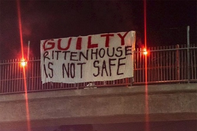 Protest sign displayed over San Diego freeway in wake of Not Guilty verdict for Kyle Rittenhouse, who was charged with murder after shooting and killing two people in Kenosha, Wisconsin during the riot that followed after Jacob Blake was shot by police there.