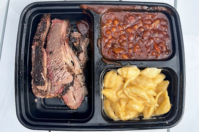 A TV dinner tray featuring smoked brisket, beans, and macaroni shells