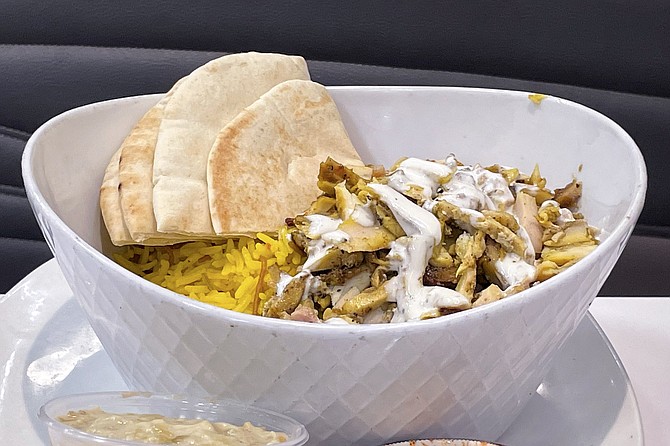A shawarma bowl of chicken served over yellow rice, with pita bread
