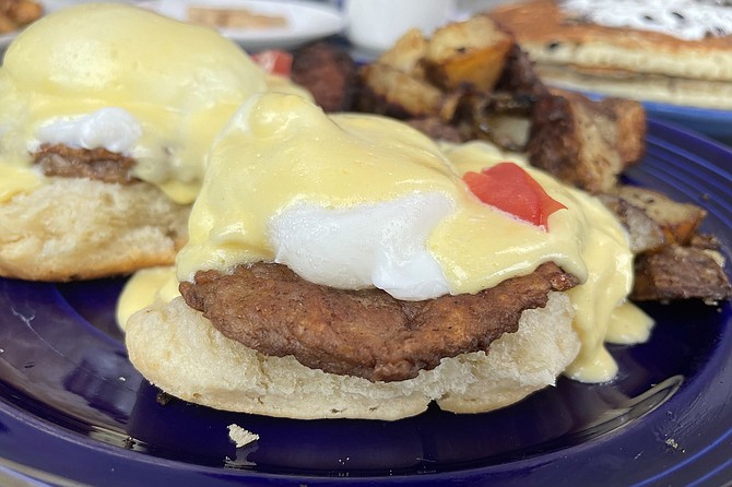 A sausage patty eggs benedict, served on a fresh biscuit