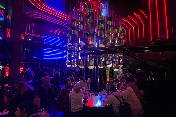 Customers dine in red and blue light as a line forms outside.