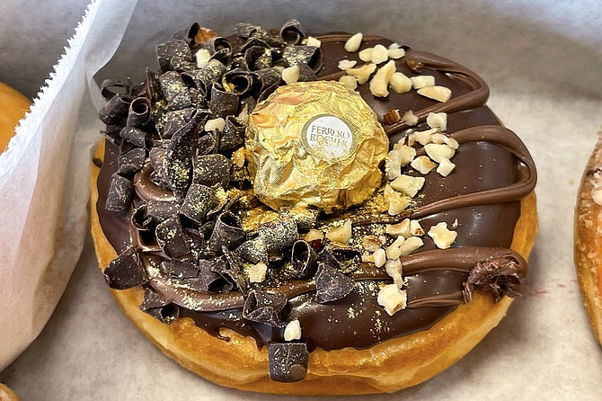 A foil wrapped Ferraro Rocher confection fits inside the hole of this chocolate-hazelnut donut.