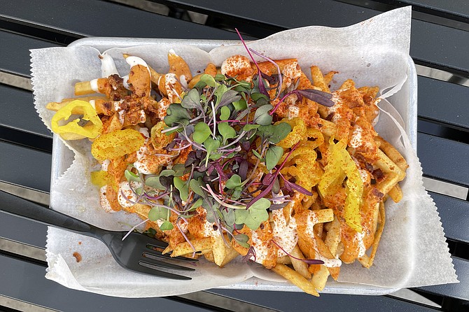 Dirty fries topped with spicy sauce, pickled peppers, and micro greens